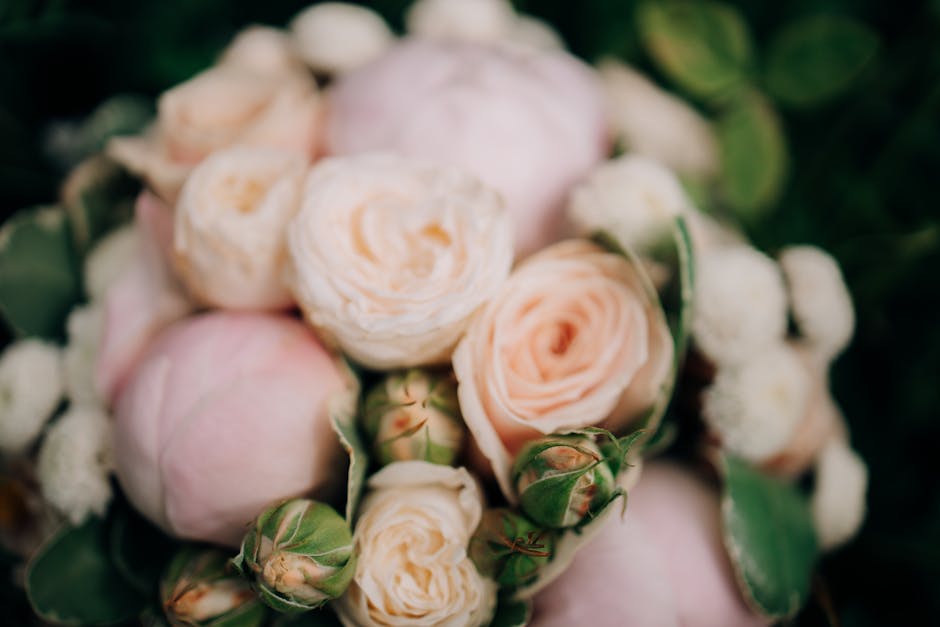 A person dressed in a vibrant pink gown with intricate beaded embellishments on the bodice holding a floral bouquet. The bouquet features large, soft green hydrangea blooms surrounded by smaller white