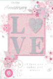 This anniversary card offers a gentle, romantic tribute to lasting love, its design as soft and intimate as a twilight walk along the quiet residential streets of Golders Green. The centrepiece is the word LOVE, created with raised, velvety glitter that gives each letter a subtle three-dimensional quality. The letters are outlined with delicate sparkle, while the interior of the O is replaced by a shimmering silver heart, its texture denser and more reflective, like a small jewel nestled within the design. Surrounding this focal point, graceful blooms unfold across the card in pastel tones of blush pink and muted mauve, their edges softened to resemble watercolour gently bleeding into the paper. Threadlike stems and curling vines link the flowers together, their lines flowing in elegant loops and swirls that suggest both movement and care, much as a florist would layer greenery through a romantic bouquet. Tiny embellishments-petals, curls, and faint butterfly silhouettes-are scattered like confetti, adding a touch of whimsy while preserving the card's calm, sophisticated mood. The backdrop is a quiet wash of pale pink, with soft gradients that create a sense of depth without drawing attention away from the central word and heart. In a refined, flowing script, the phrases On Our Anniversary and I love you today and always are written across the design, their gentle curves echoing the floral linework. The overall composition feels tender and sincere, a paper keepsake that would pair beautifully with pastel anniversary flowers delivered to a loved one in the Golders Green area, capturing the essence of a relationship that is both gentle and enduring.